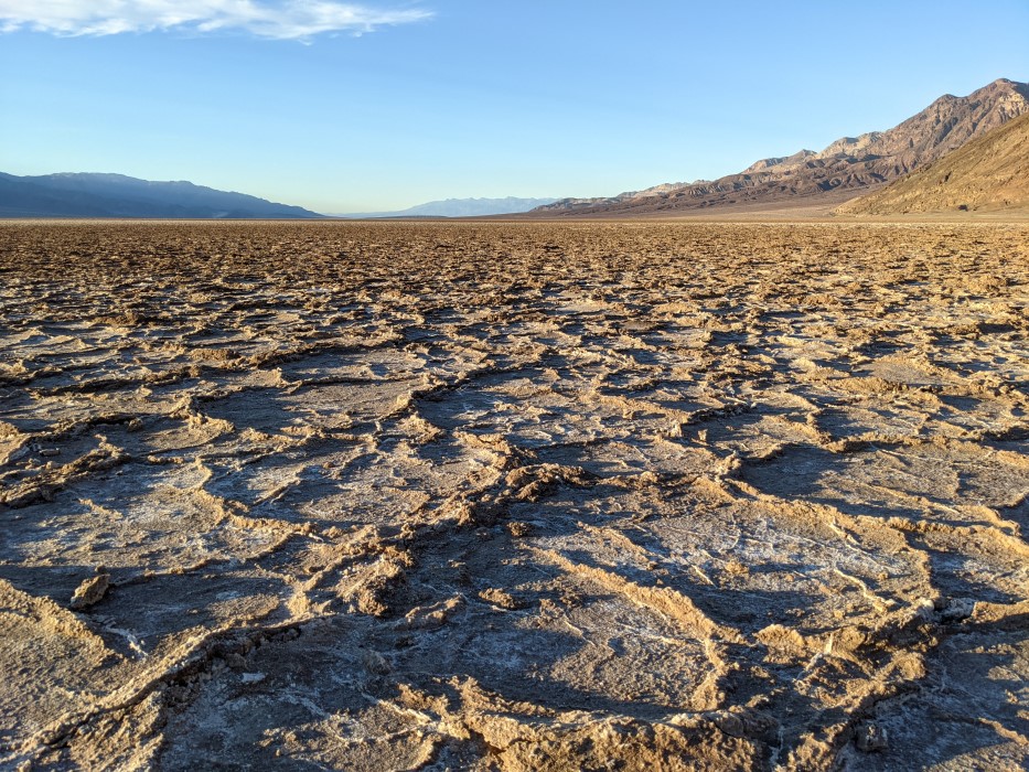 The ground is brown, free of life and covered with ridges in roughly round hexagonal patterns about an inch high and a foot across, going all the way until mountains in the distance