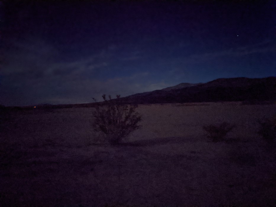 Similar landscape, but very dark. You can still see the mountains and nearby bushes, but that's about it.