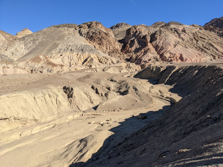 Looking out over a small canyon, maybe two stories high, that snakes back to some mountains. All the rocks are bare.